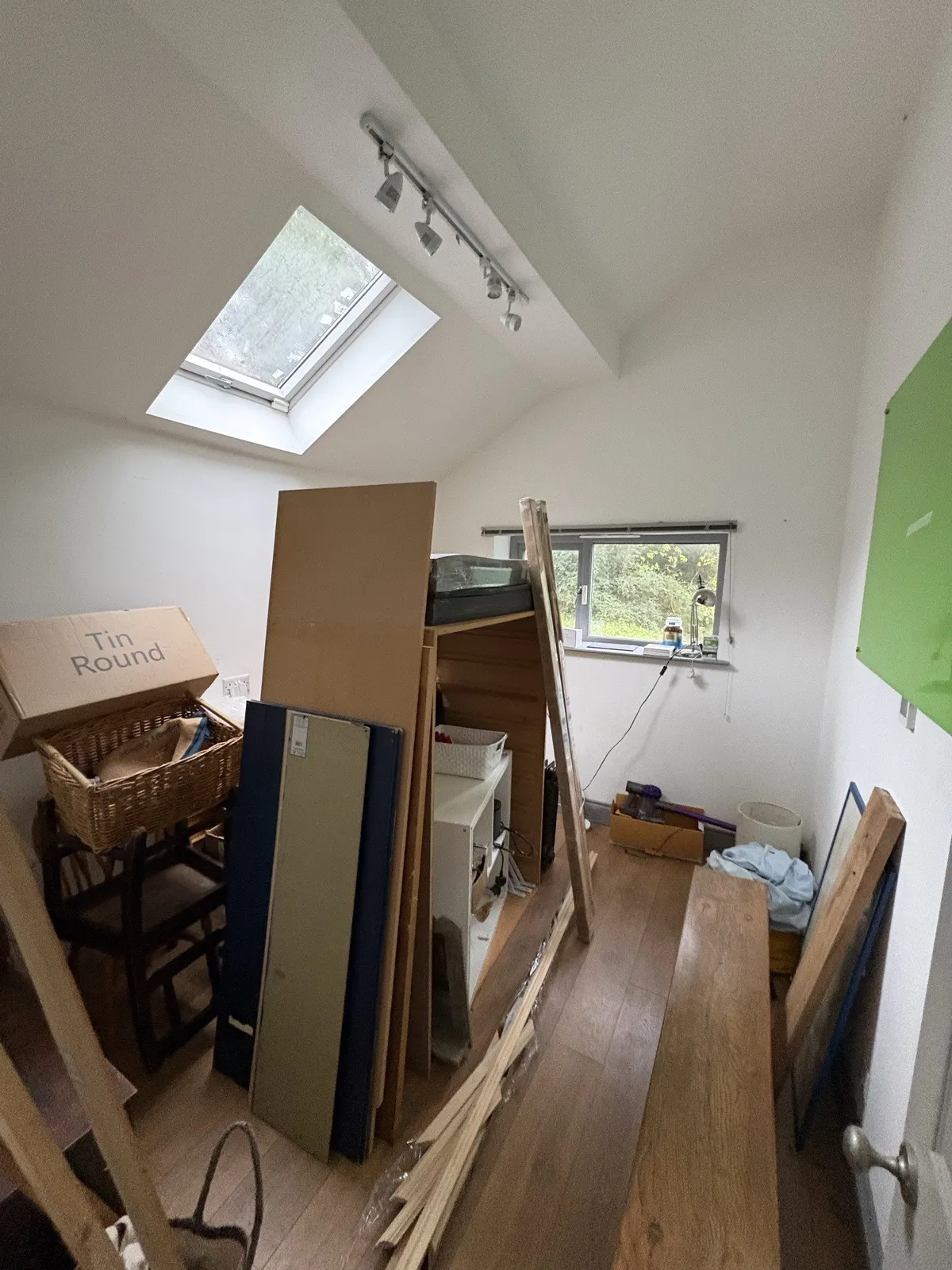 Bedroom 1 before work: boards and furniture stacked under a skylight