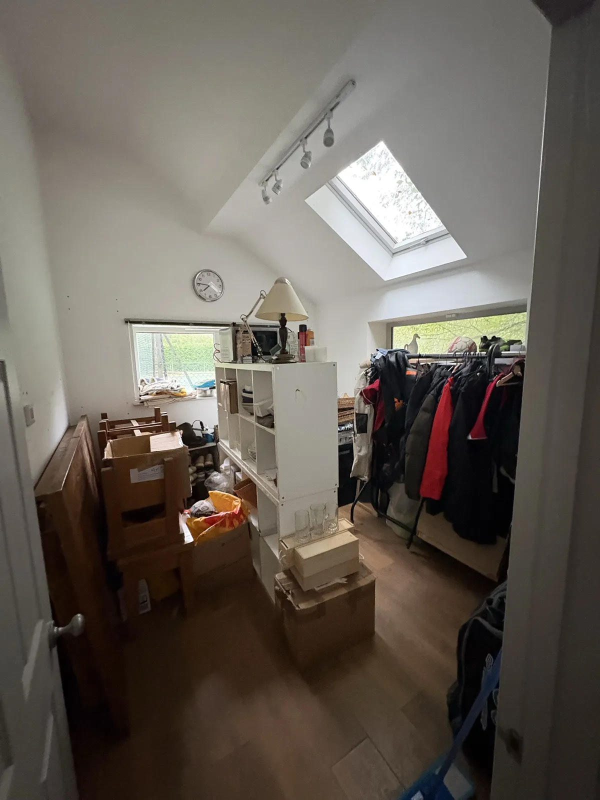 Bedroom 2 before work: a clothes rail, boxes and shelving under a skylight